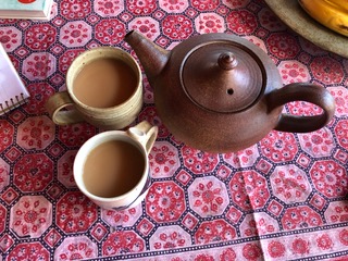 Two mugs of tea and a teapot on an Indian print cloth. We sat down to drink tea and talk about my vision for tidying up.